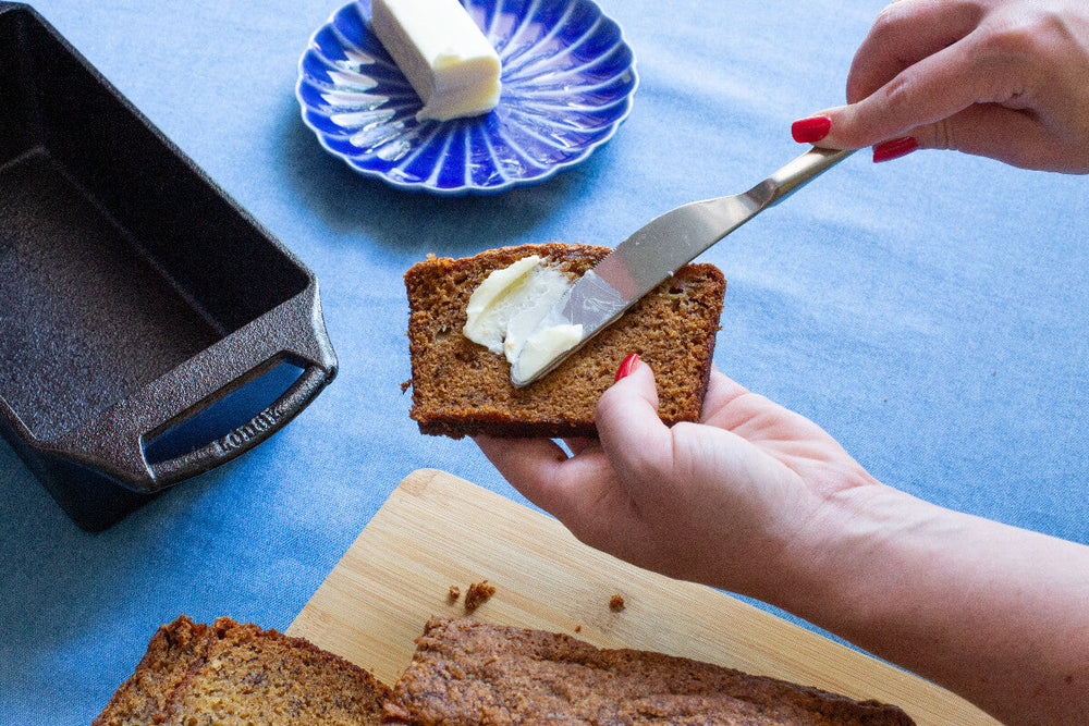 Someone buttering a piece of bread