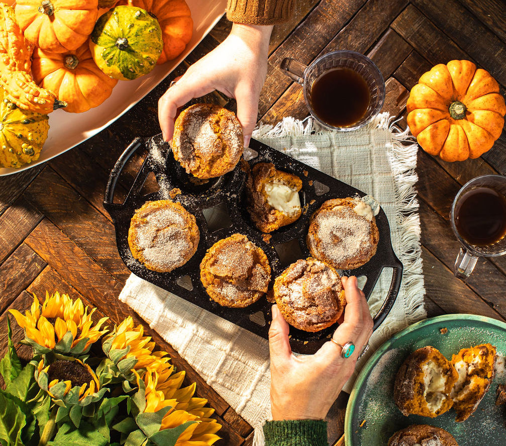 People taking pumpkin corn muffins out of pan.
