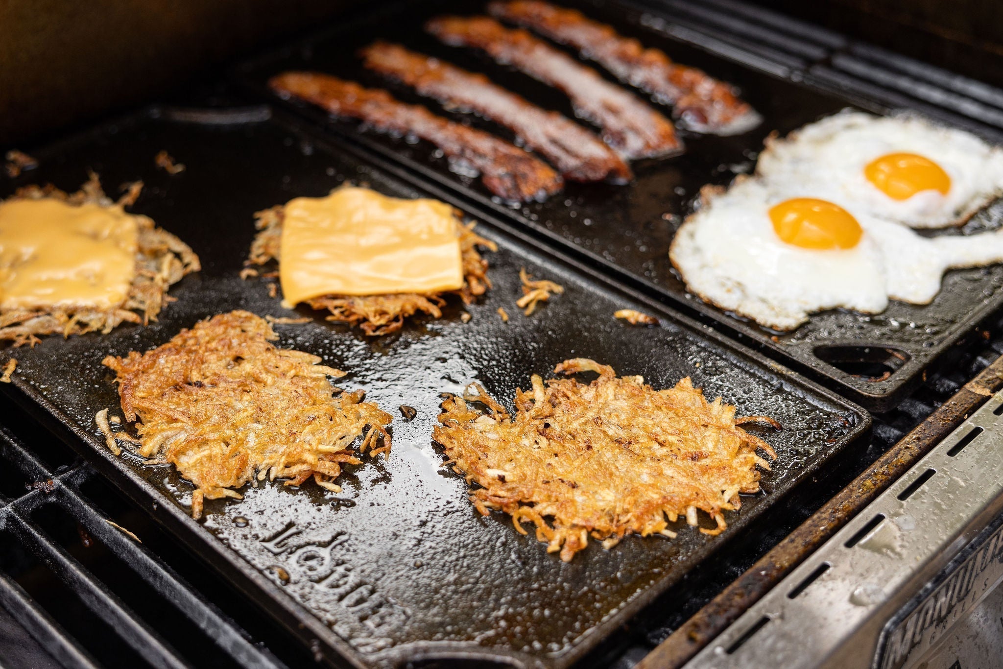 Hashbrowns cooking on hot griddle over a grill.