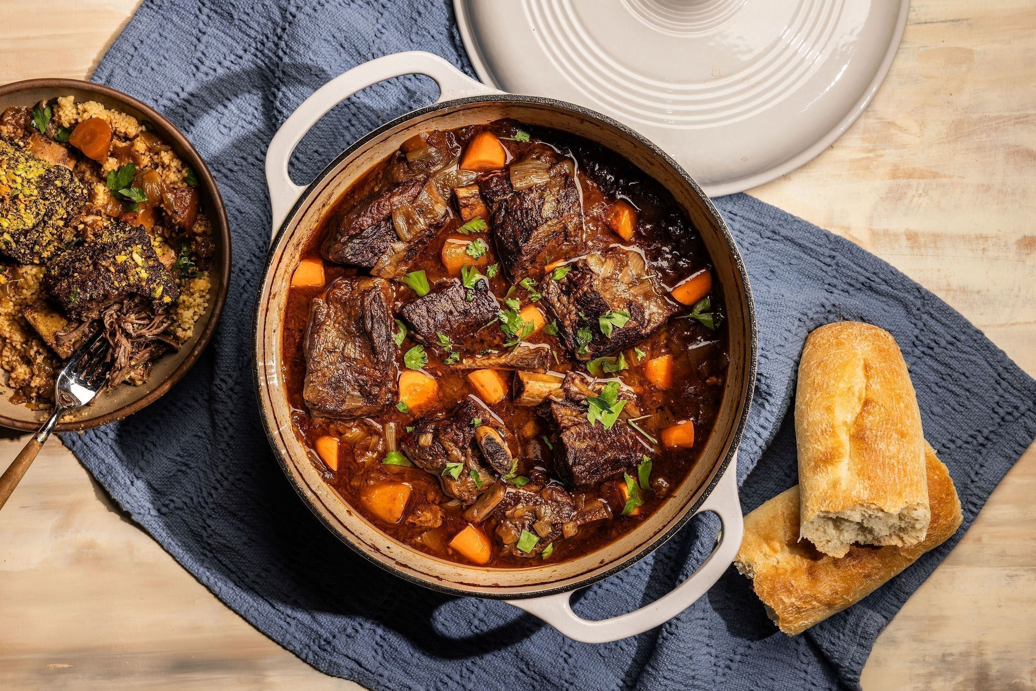 Dutch oven with freshly prepared braised ribs, served with bread.
