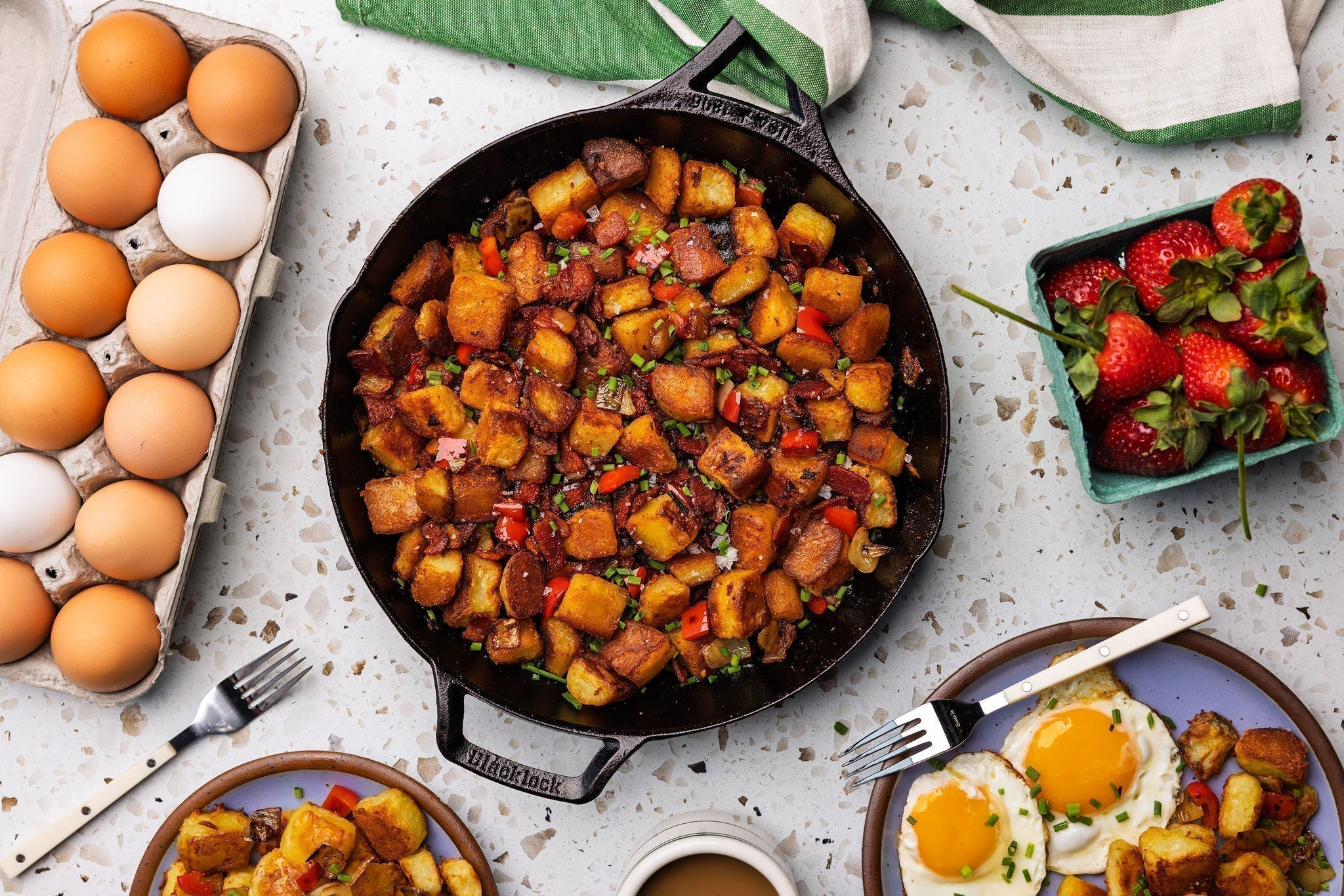 Top view of breakfast potatoes near eggs and strawberries, served on table.