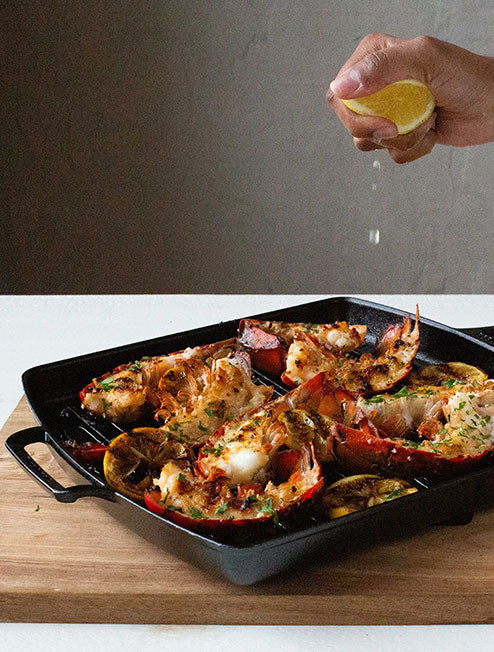 Someone squeezing lemon juice over freshly prepared lobster tails.