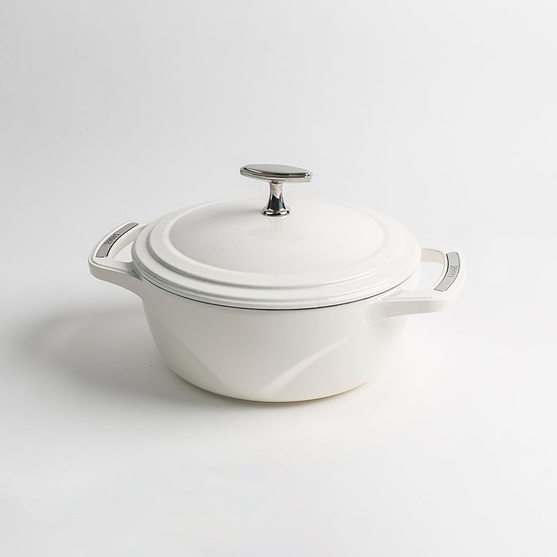 White enameled cast iron Dutch oven with a lid on a white background