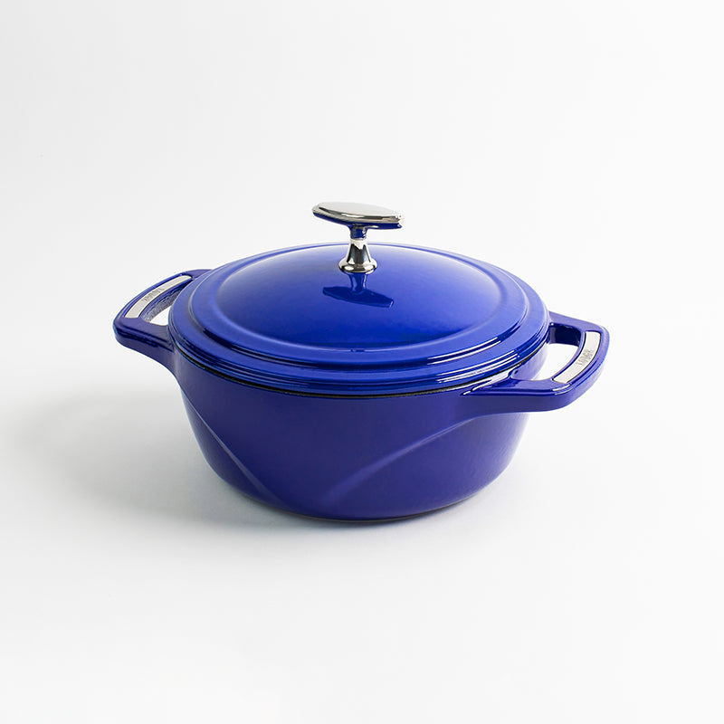 Blue enameled cast iron Dutch oven with a lid on a white background