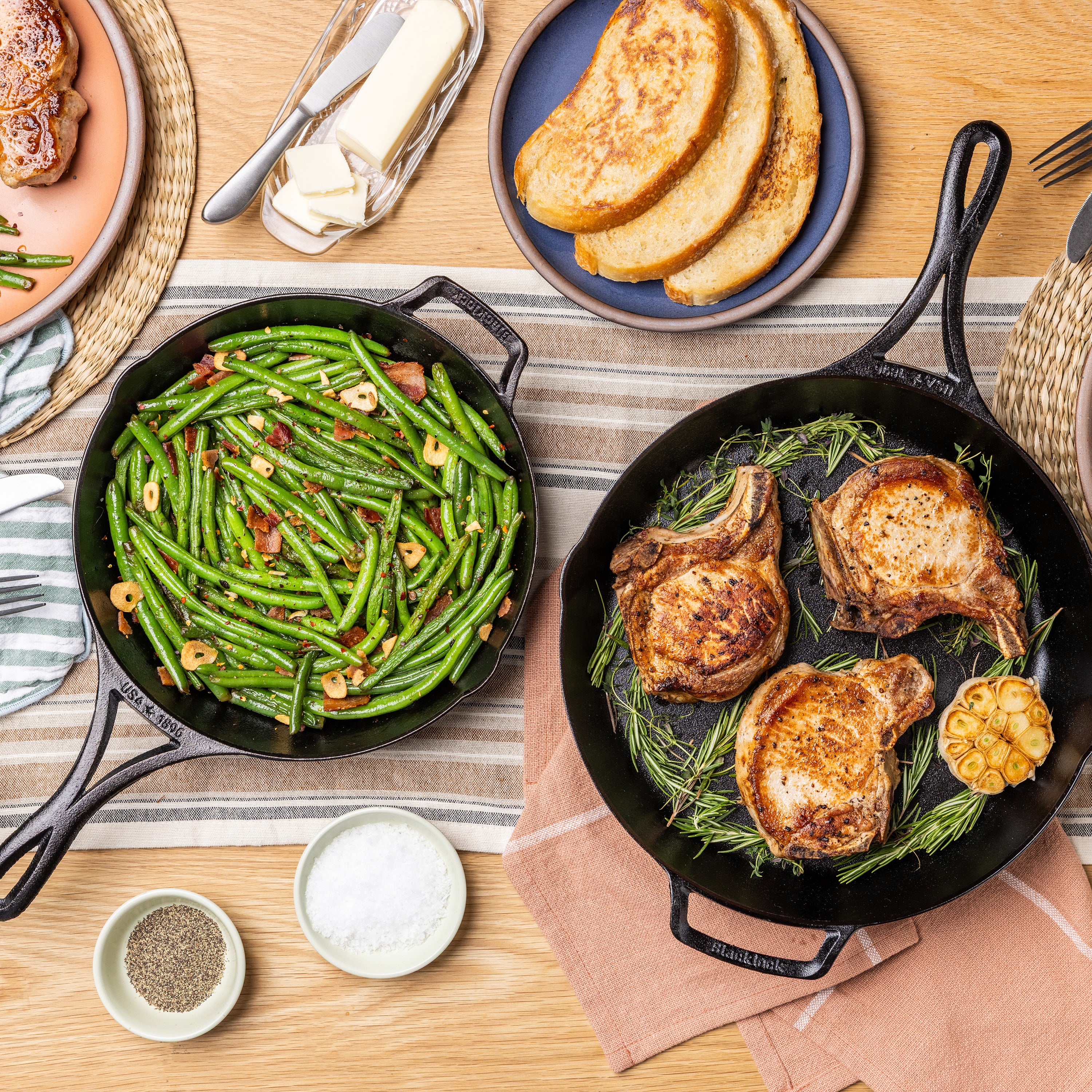 Both skillets served on table, one with green beans the other with pork chops.