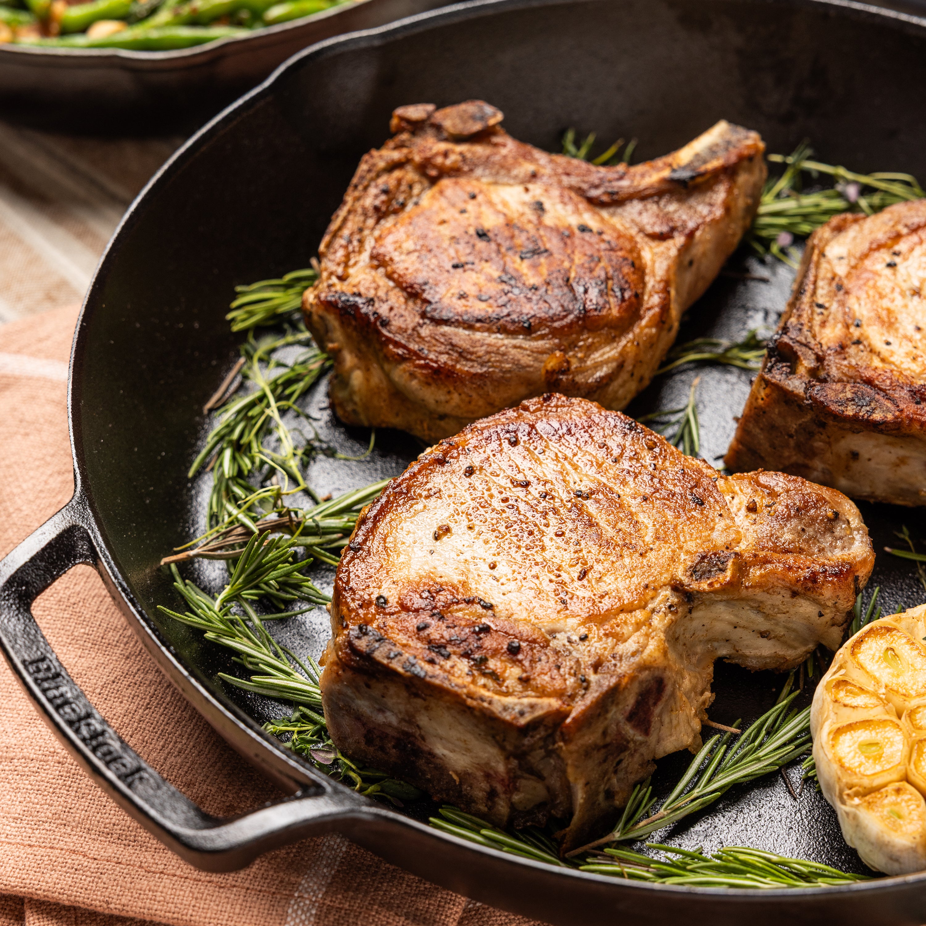 Pork chops, cooked and served in skillet with rosemary.