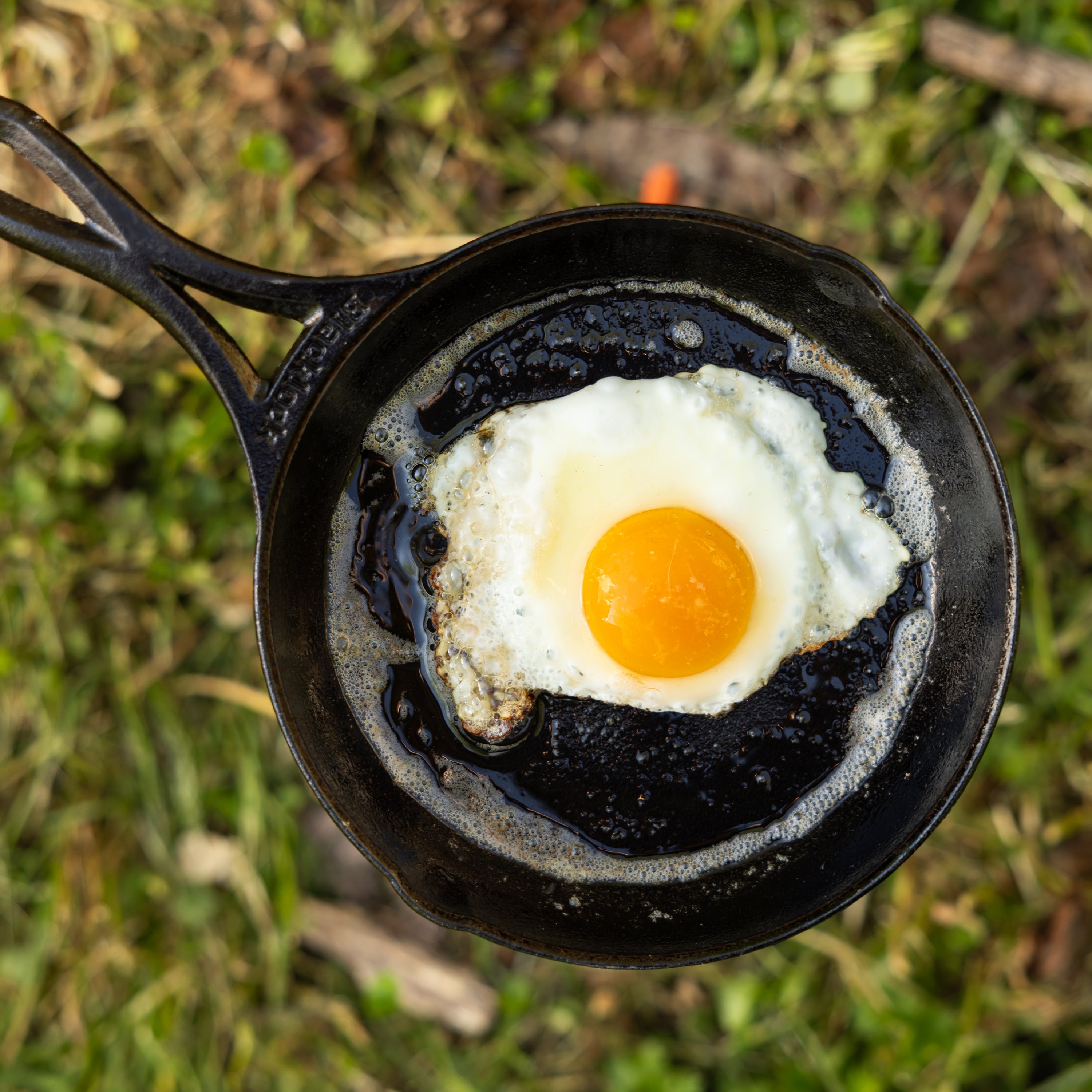 Top view of an egg cooking in skillet outside.