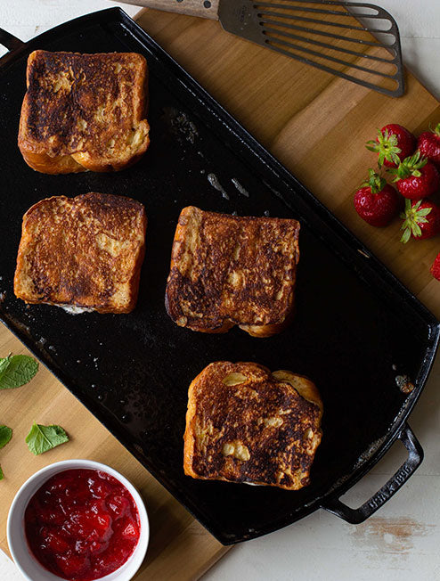 Grilled cheese freshly prepared and served on griddle with strawberry jam.