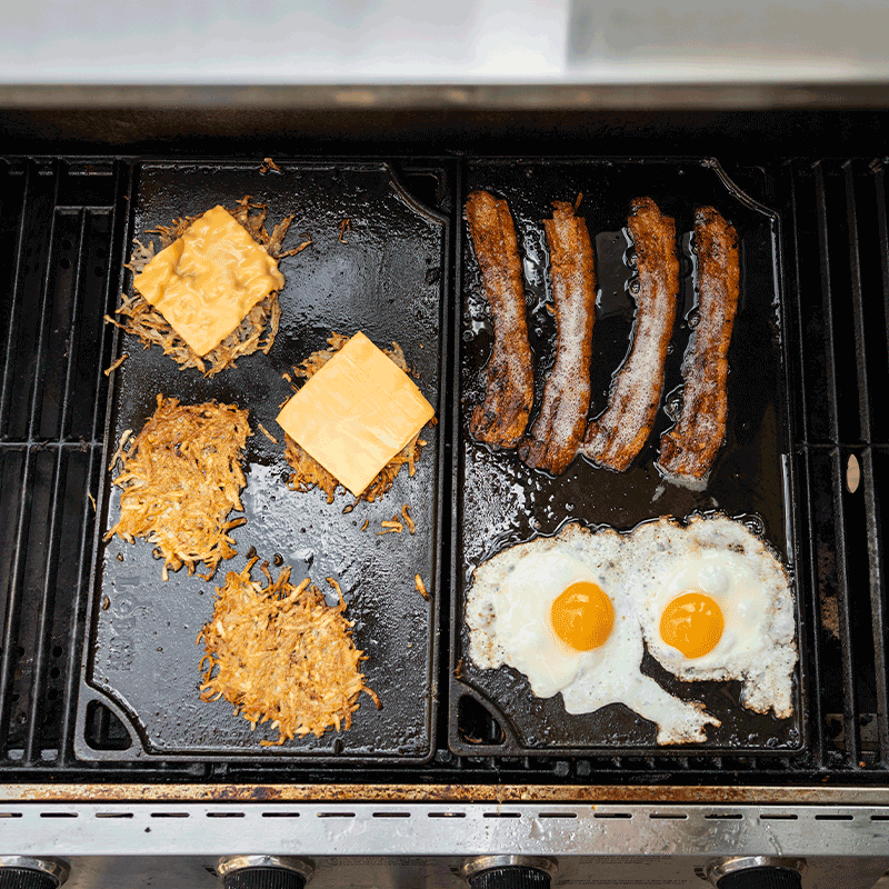 Freshly made bacon, eggs, and hashbrowns using 2 griddles on a grill.