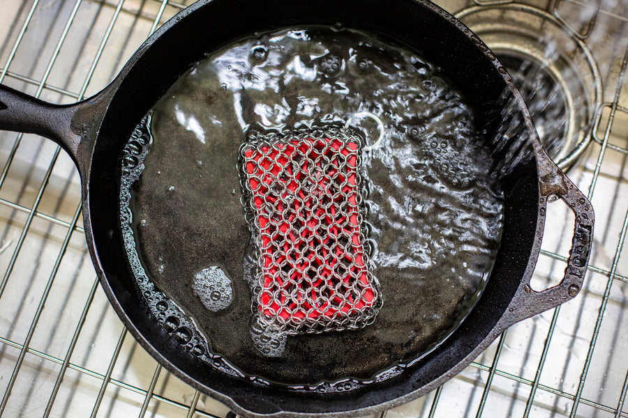 Chainmail scrubber being used to wash skillet.