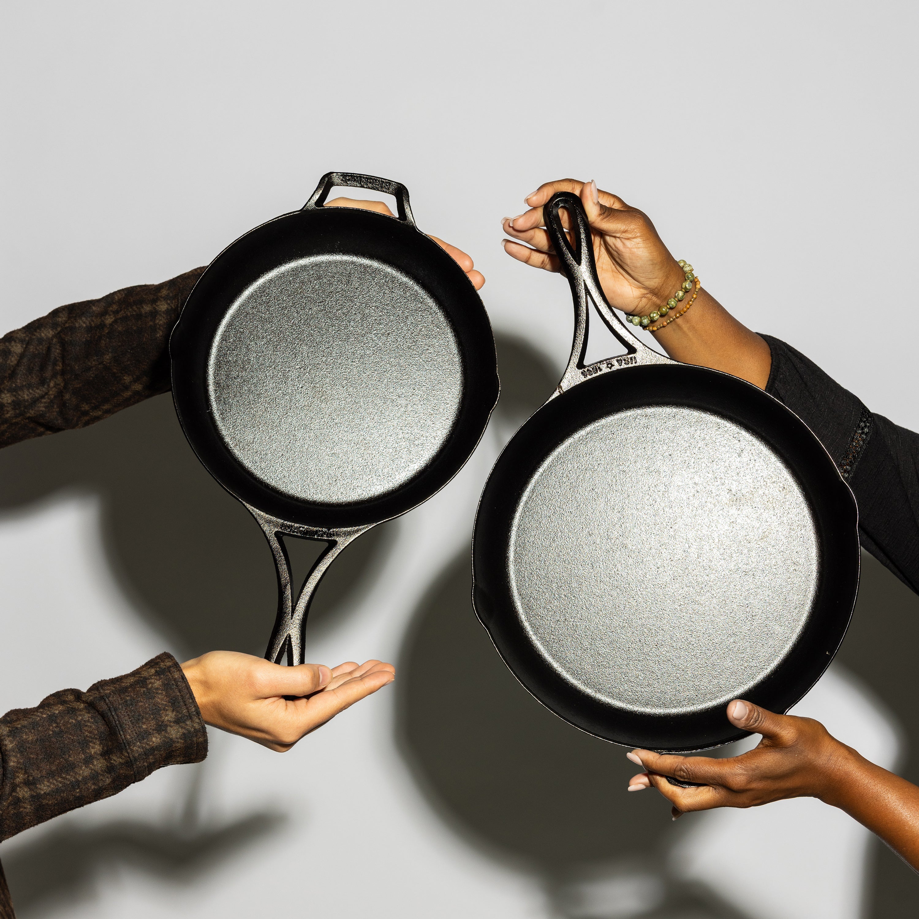 Two people holding skillets side by side.