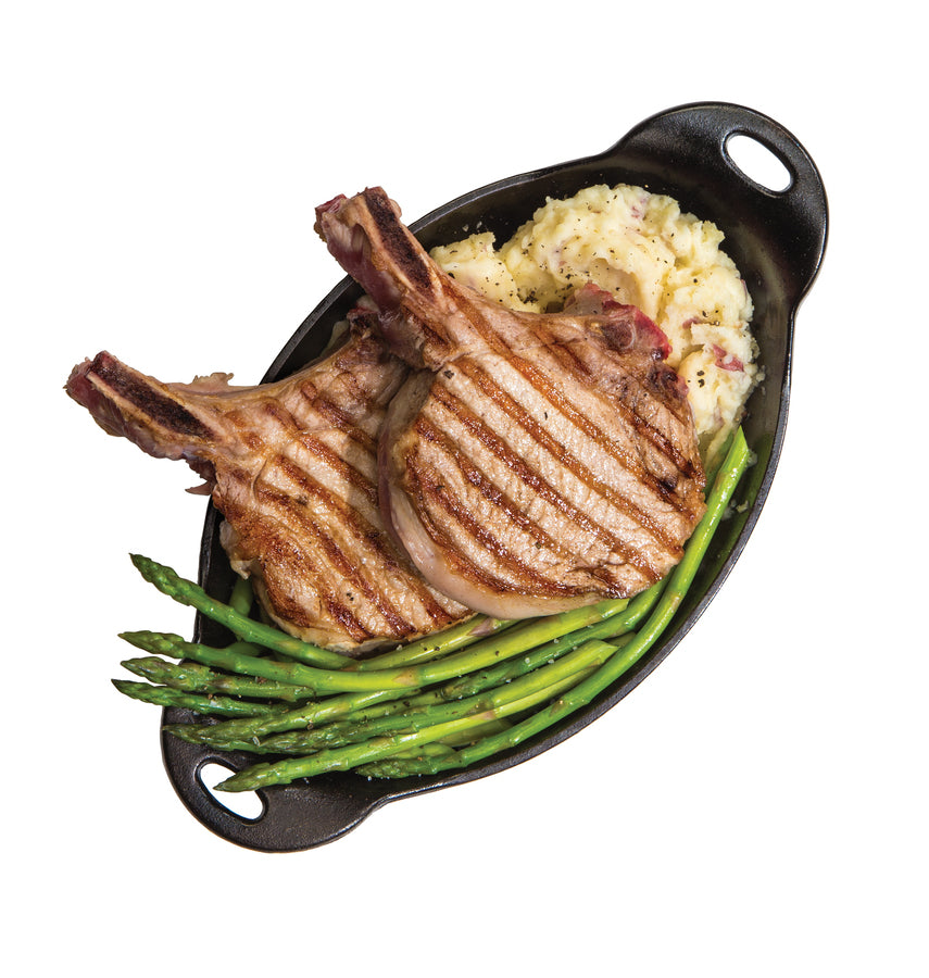 Fresh pork chops, asparagus, and mashed potatoes served in product.