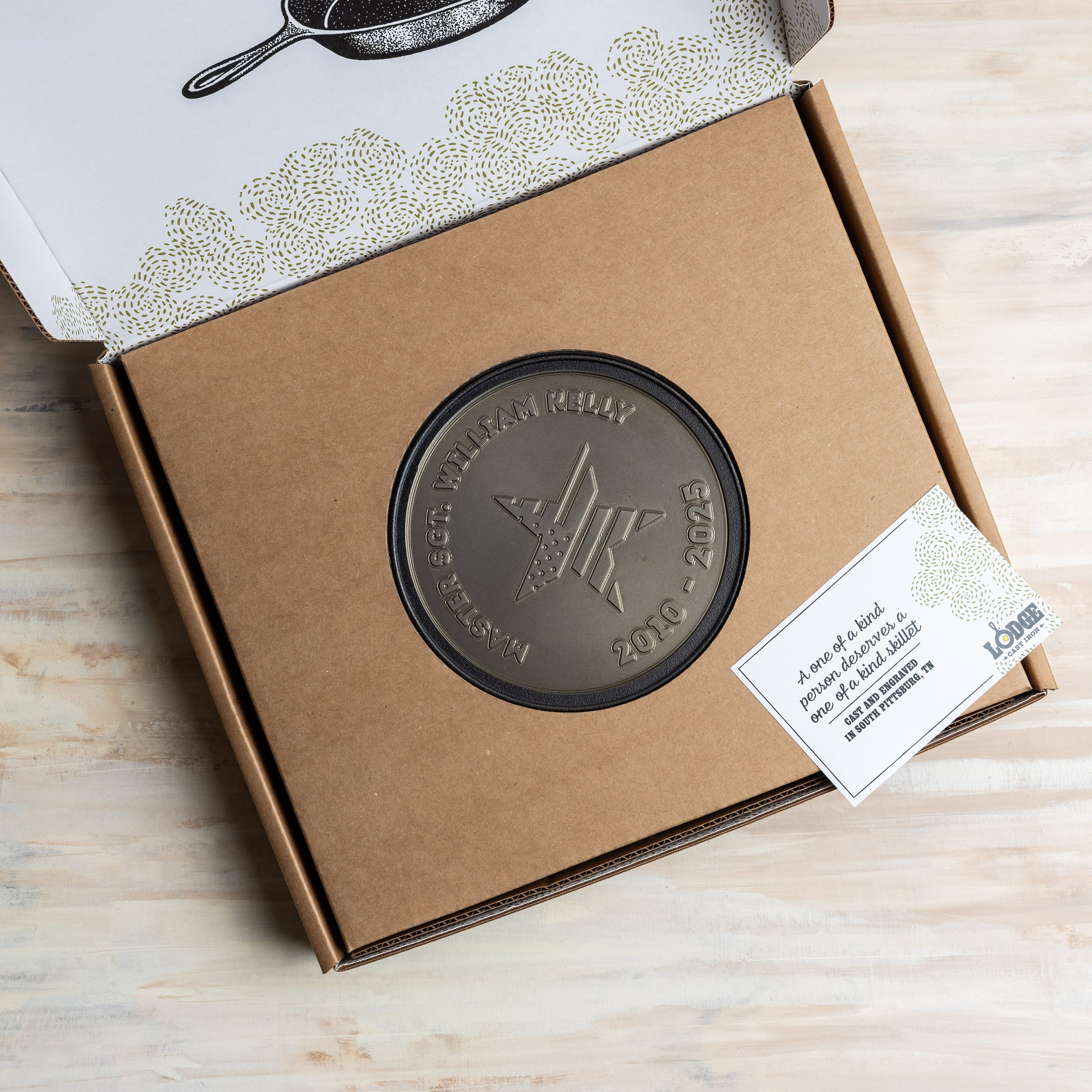 Bronze engraved skillet with star design on a cardboard box with a label