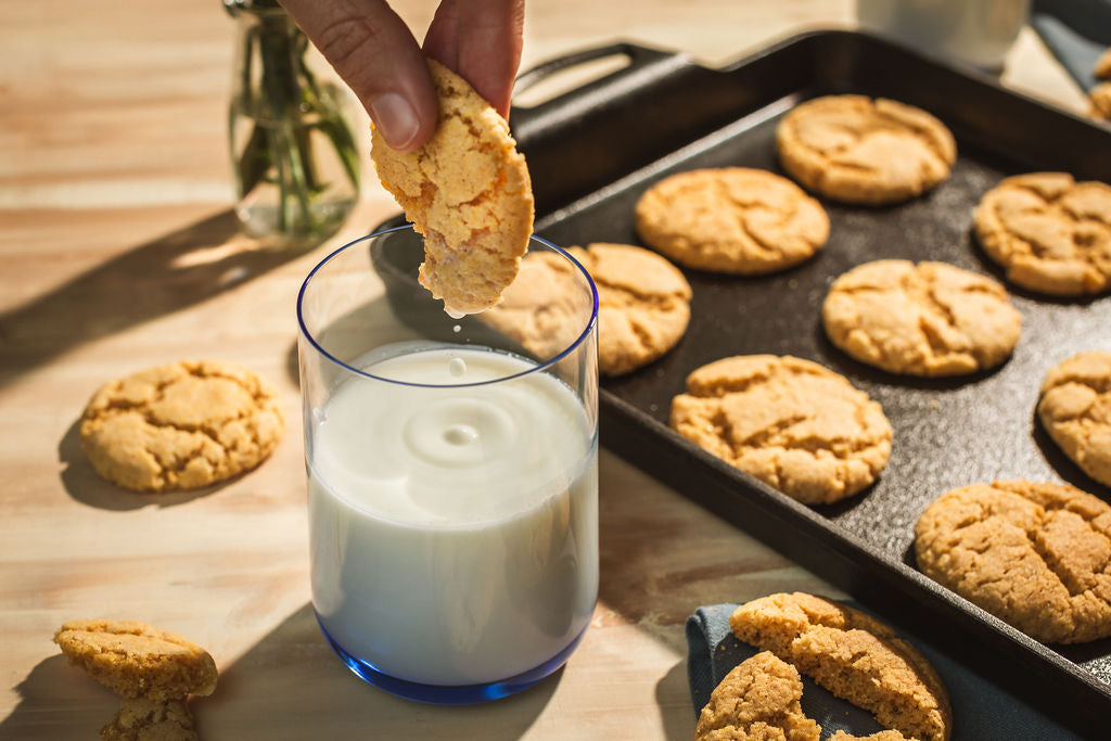 Someone dipping cookie into glass of milk.