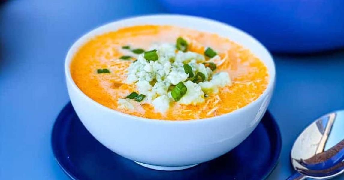 Buffalo chicken soup served in bowl on blue table.