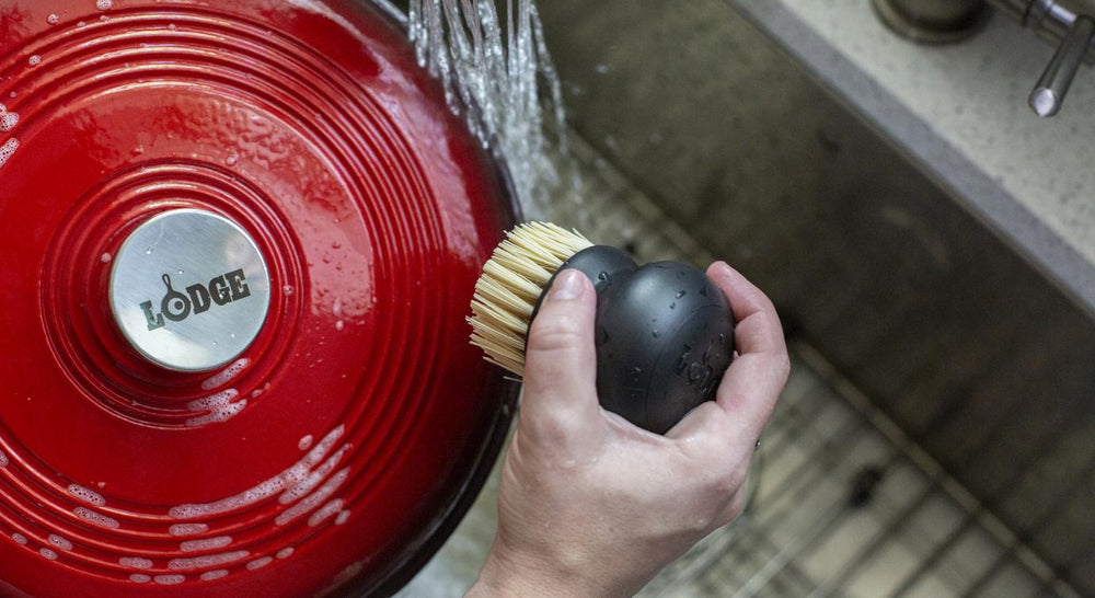 Someone scrubbing dutch oven in sink