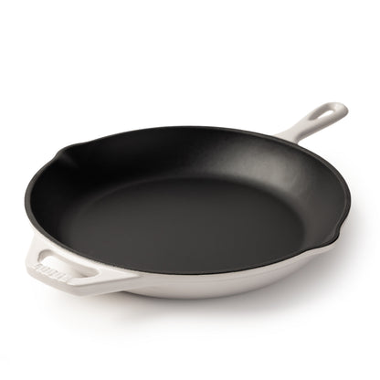 An enameled cast iron skillet with a black interior and a white exterior, featuring a single loop handle on the right and a side handle on the left, photographed on a clean white background.