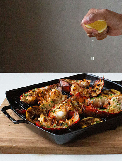 Someone squeezing lemon juice over freshly prepared lobster tails.
