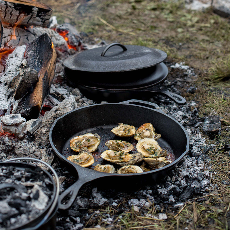 Mussels being roasted in skillet at campfire.