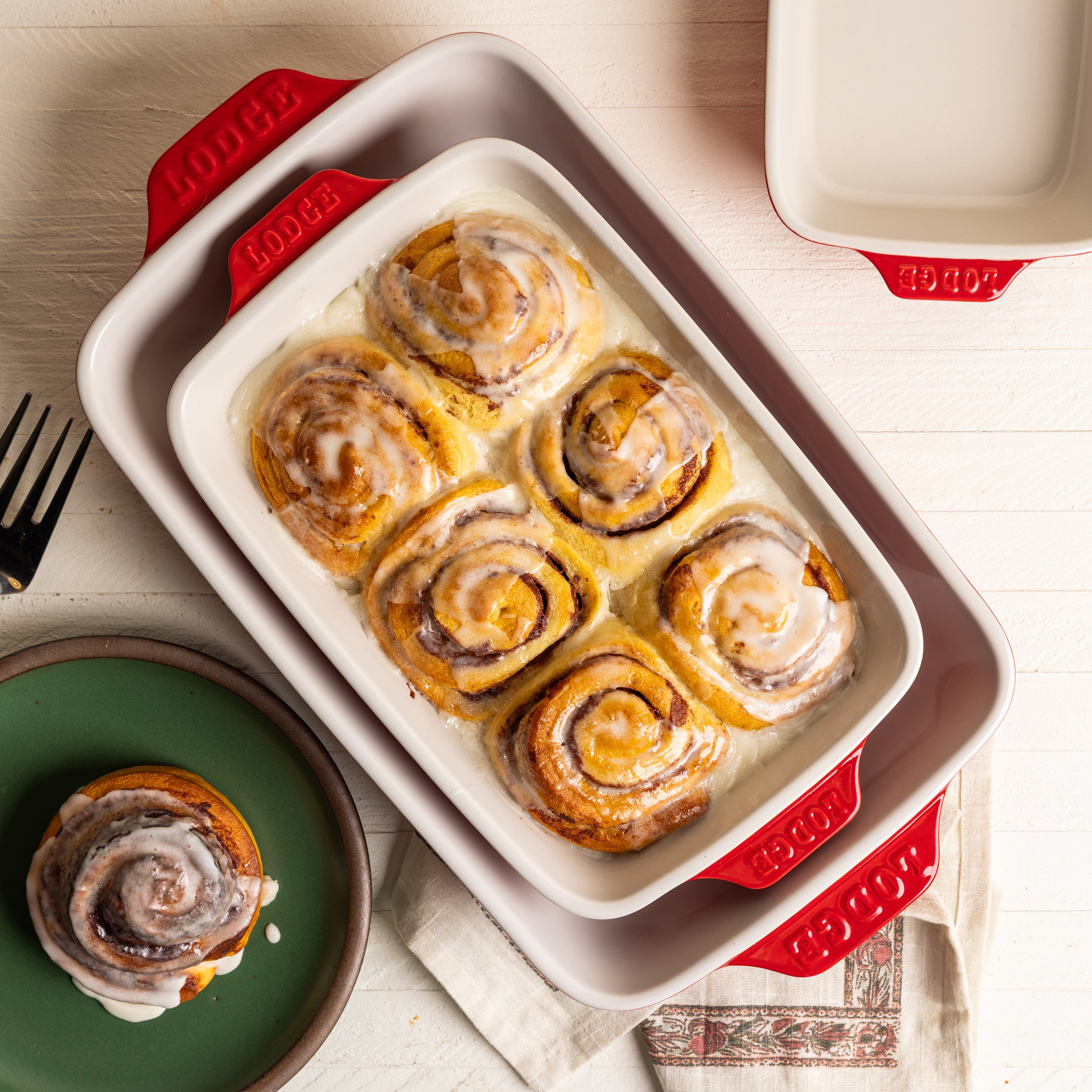 Baked cinnamon rolls in a red and white baking dish.