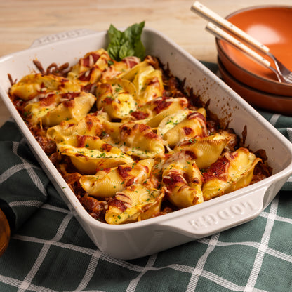 Baked pasta shells in a oyster colored stoneware baking dish on a checkered tablecloth