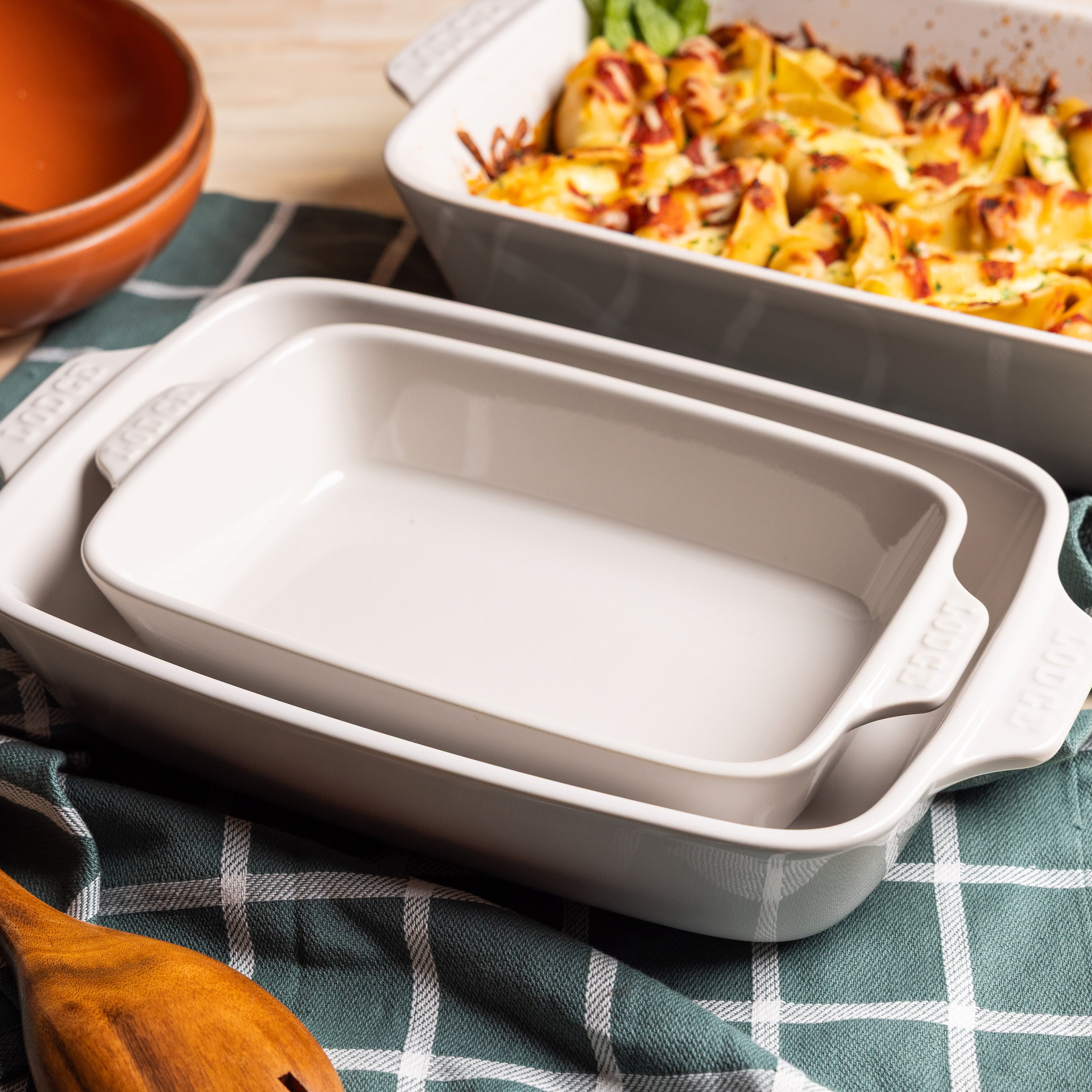 Set of ceramic baking dishes alongside a dish of pasta.