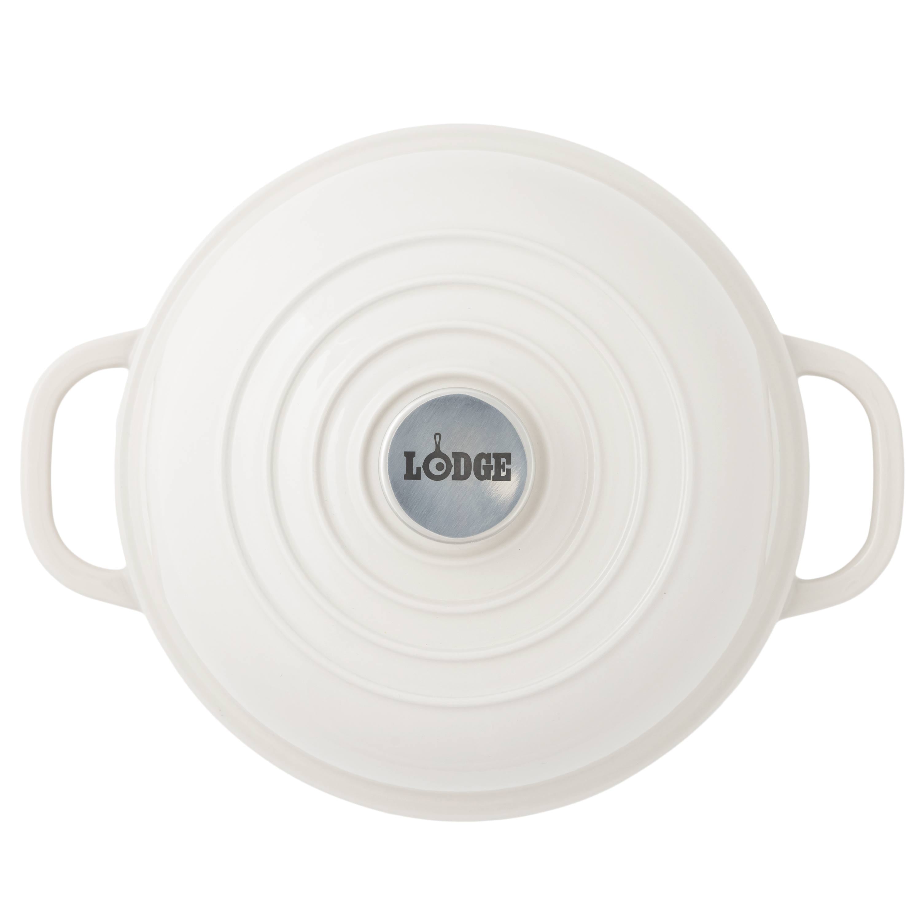Top-down view of a white Lodge bread oven with side handles and a circular silver logo plate in the center, set against a plain white background.