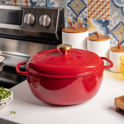 Red cast iron cookware on a kitchen counter with colorful tiles in the background