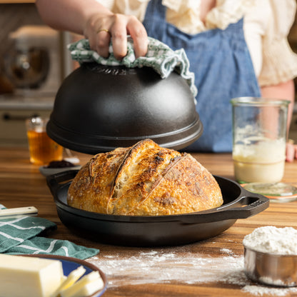 Someone removing lid from bread oven after baking.