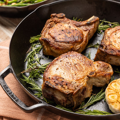 Pork chops, cooked and served in skillet with rosemary.