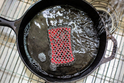 Chainmail scrubber being used to wash skillet.