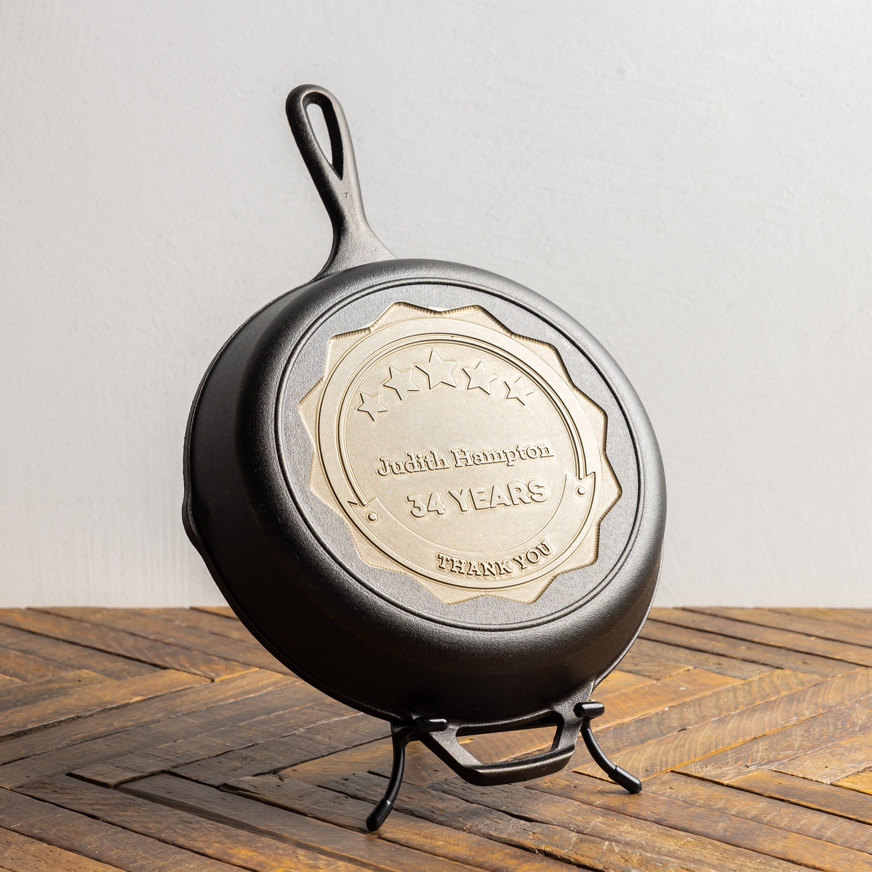 Black cast iron skillet with a gold engraved plaque on a wooden surface