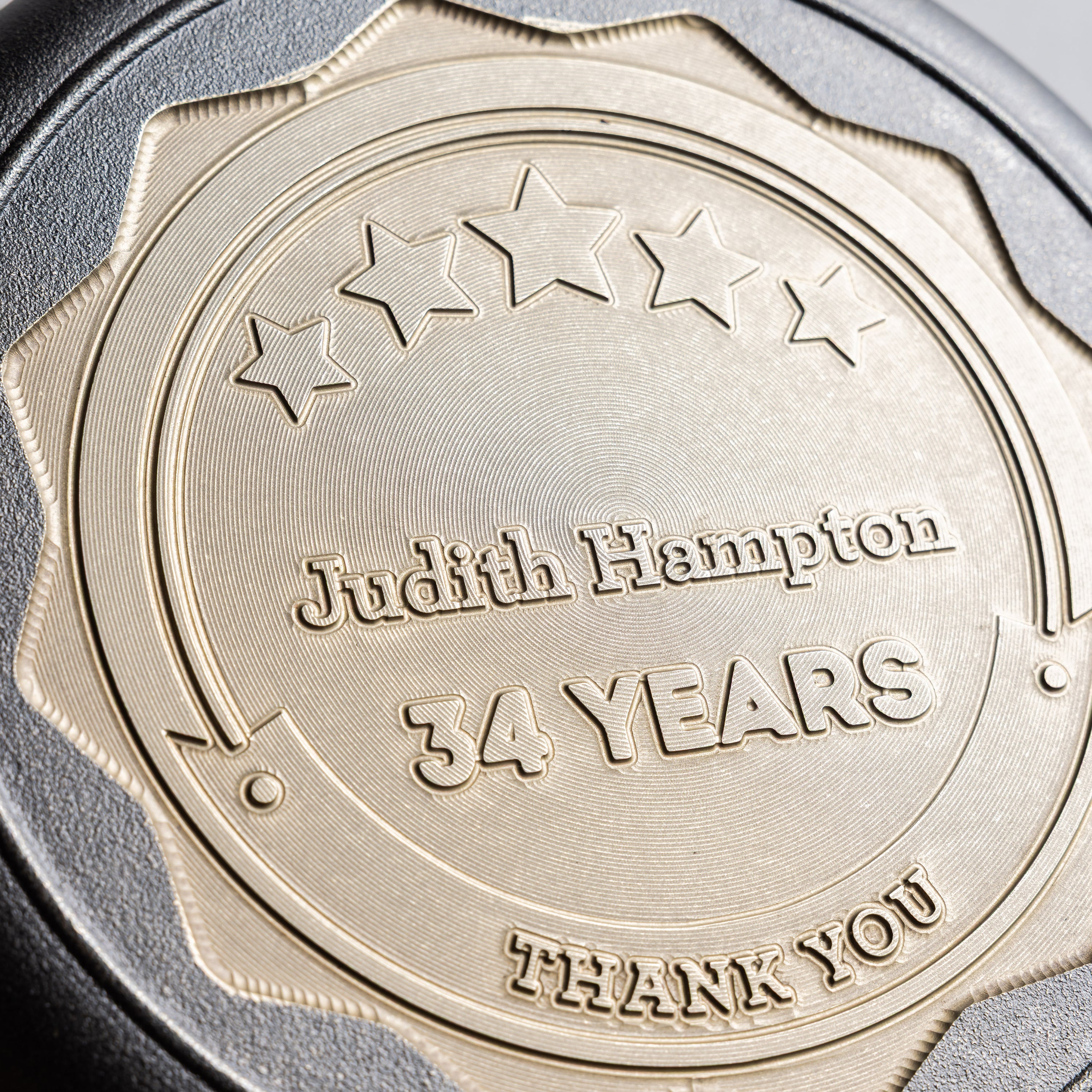 Close up of skillet with engraved text 'Judith Hampton 34 YEARS THANK YOU' on a bronze background.