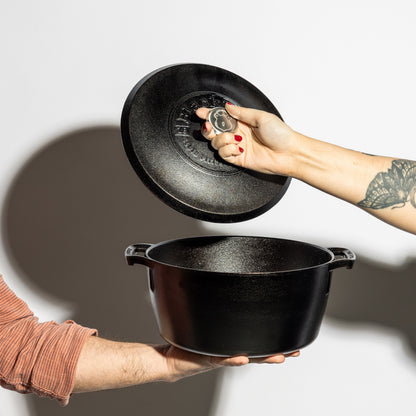Someone holding dutch oven while someone else lift's the lid.