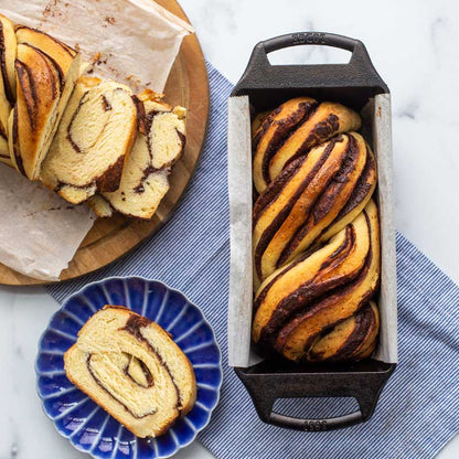 Chocolate babka loaf prepared and served in pan lined with parchment paper.