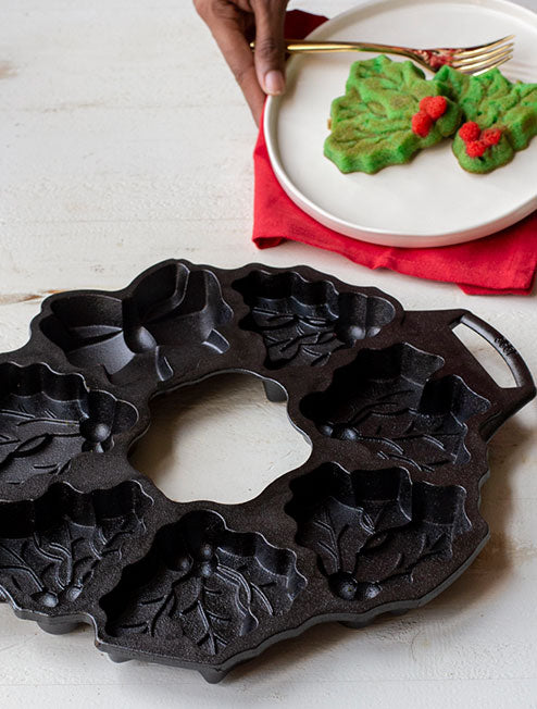 Someone with a plate of mistletoe cookies near pan.