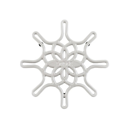 A white enameled cast iron trivet with a geometric snowflake-like pattern.