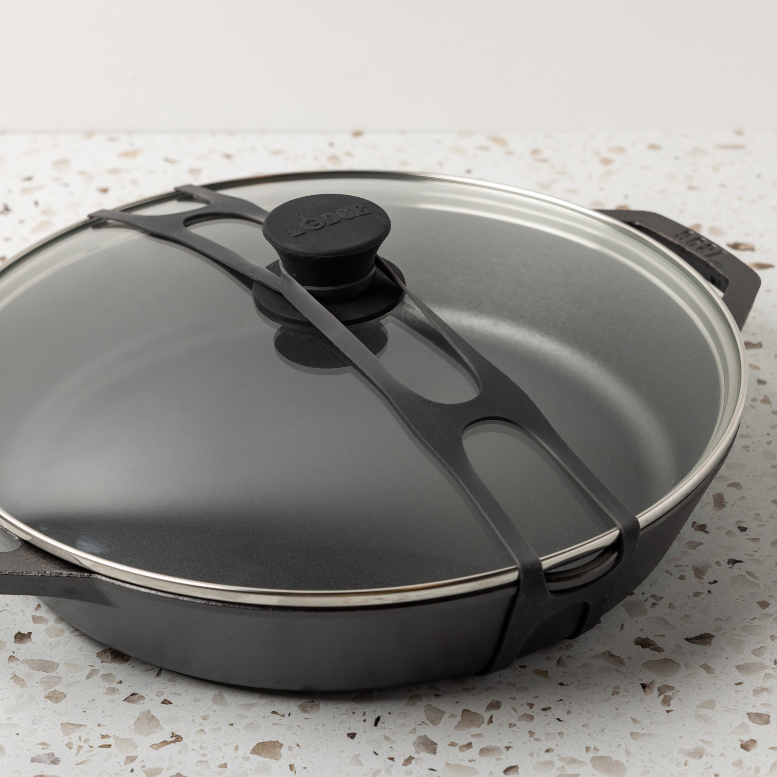 Close up shot of black lid latch being used on our everyday pan and glass lid.