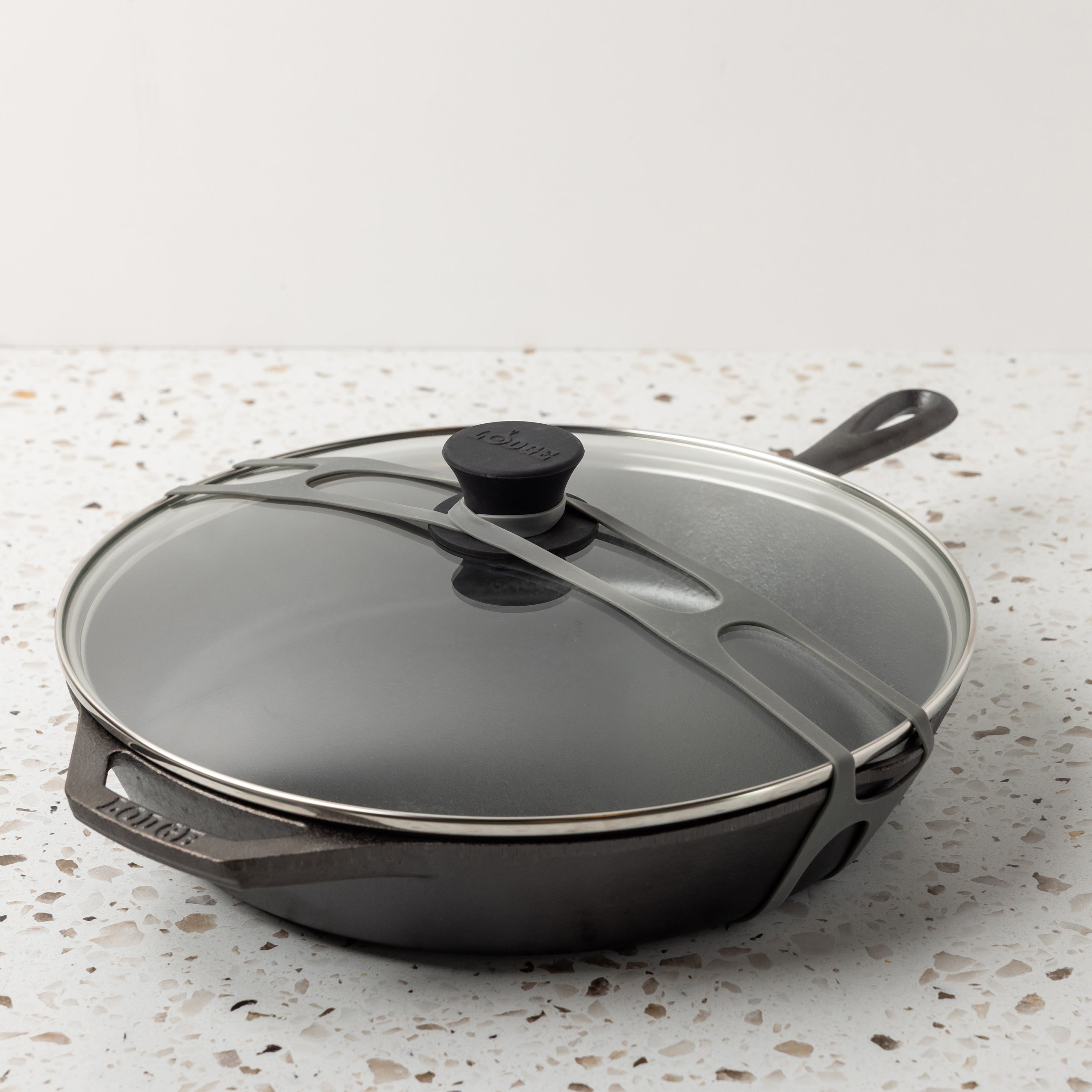Gray lid latch being use with a glass lid and classic skillet.