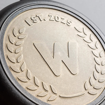 Close-up of bronze engraving on back of skillet, center initial in a sanserif font.