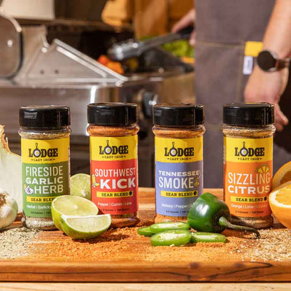 Lodge seasoning bottles on cutting board surrounded by limes, peppers, and spices.