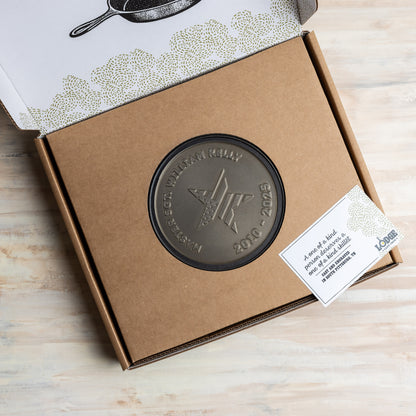 Bronze engraved skillet with star design on a cardboard box with a label