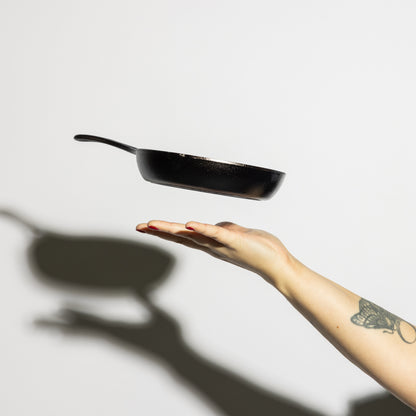 Someone tossing skillet in air, showing side profile and how product is light weight.