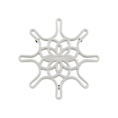 A white enameled cast iron trivet with a geometric snowflake-like pattern.