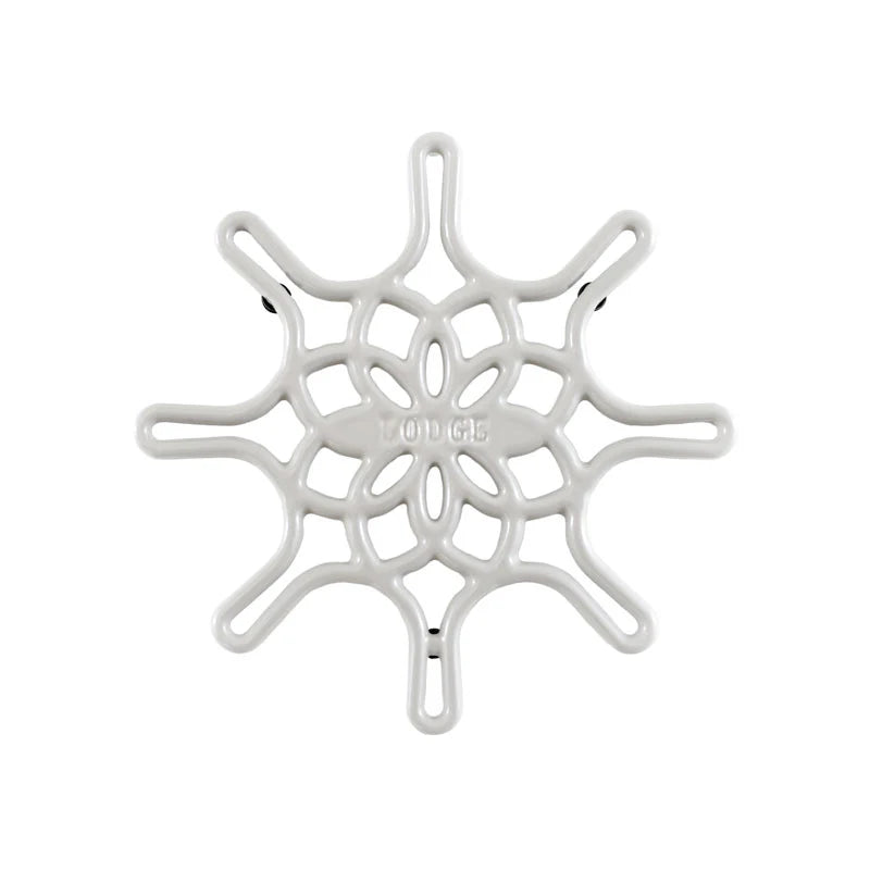 A white enameled cast iron trivet with a geometric snowflake-like pattern.