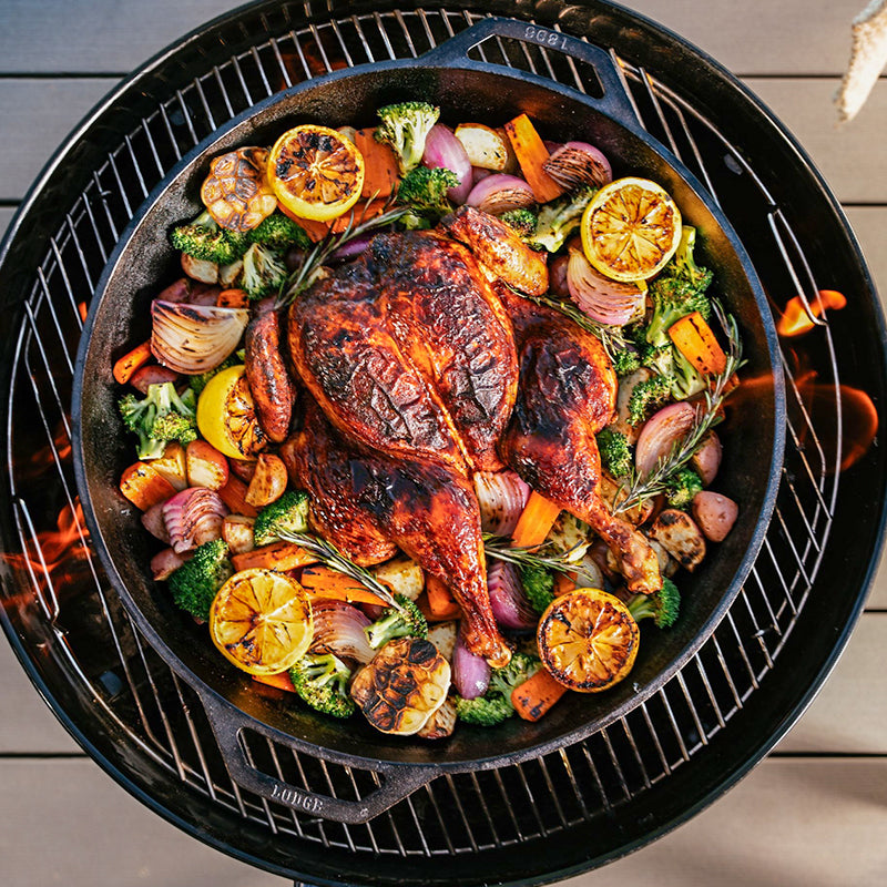 Chicken being cooked with veggies in pan.