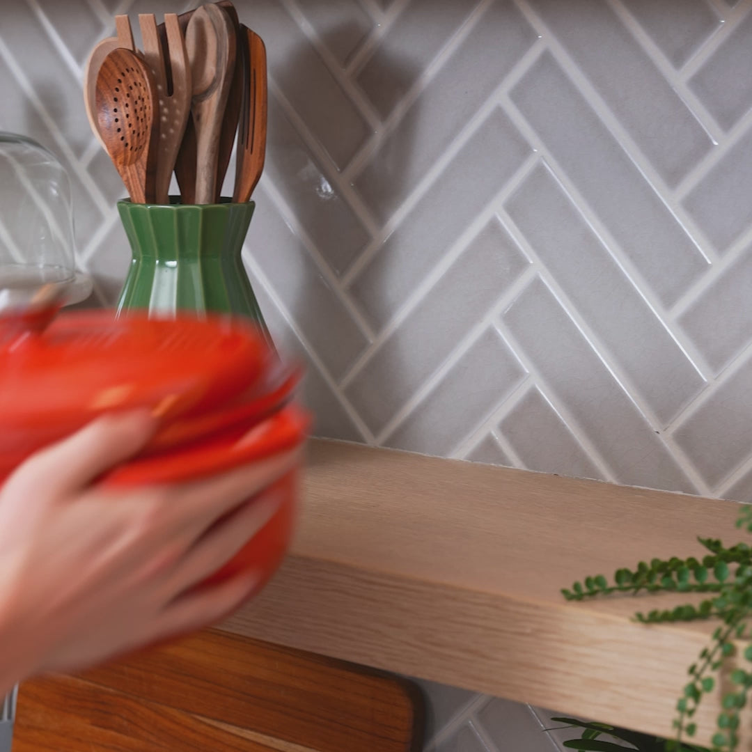 Someone placing dutch oven on kitchen shelf.