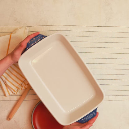 Indigo, stoneware casserole dish being placed on counter.