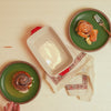 Fresh cinnamon rolls, served beside cherry red ceramic dish.
