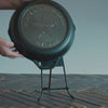 Someone placing personalized skillet on the Lodge Skillet Display stand.